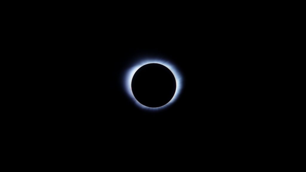 A black circle is surrounded with blue light, suggestive of an eye, to illuminate the concept of nigredo.